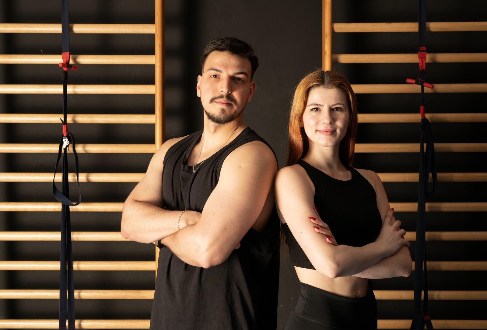 Momentum TV eğitmenleri Eda Hoca ve Gökhan Hoca, duvar barları ve TRX askıları önünde